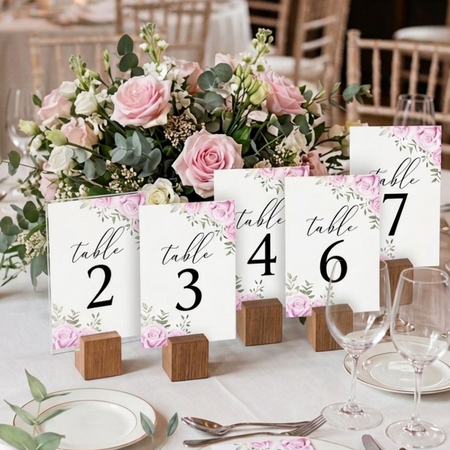 Floral centerpiece with table number cards on a decorated table.
