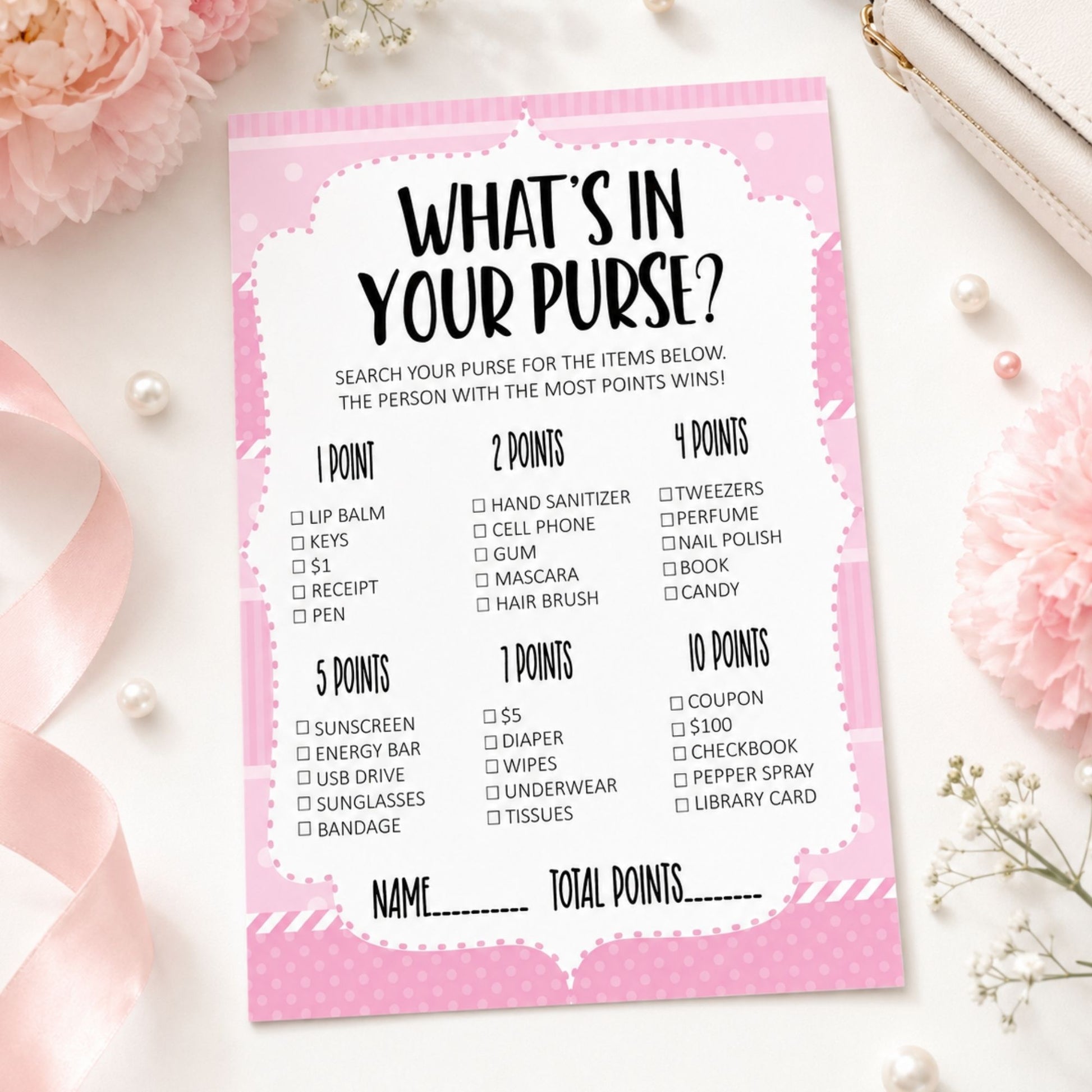 A pink and white 'What's in Your Purse?' party game score card styled in a flat-lay with pink flowers, pearls, and a white leather strap.