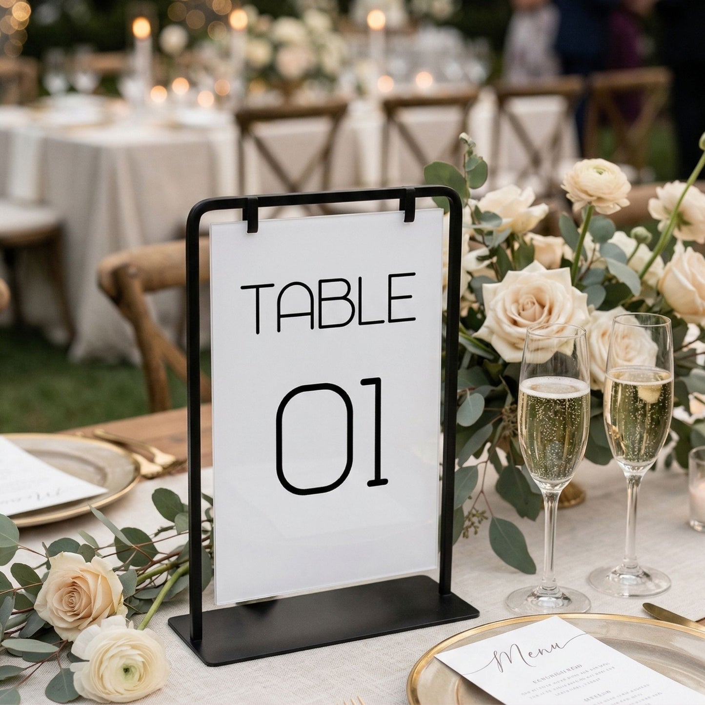 Table number sign '01' on a decorative table with flowers and champagne glasses.