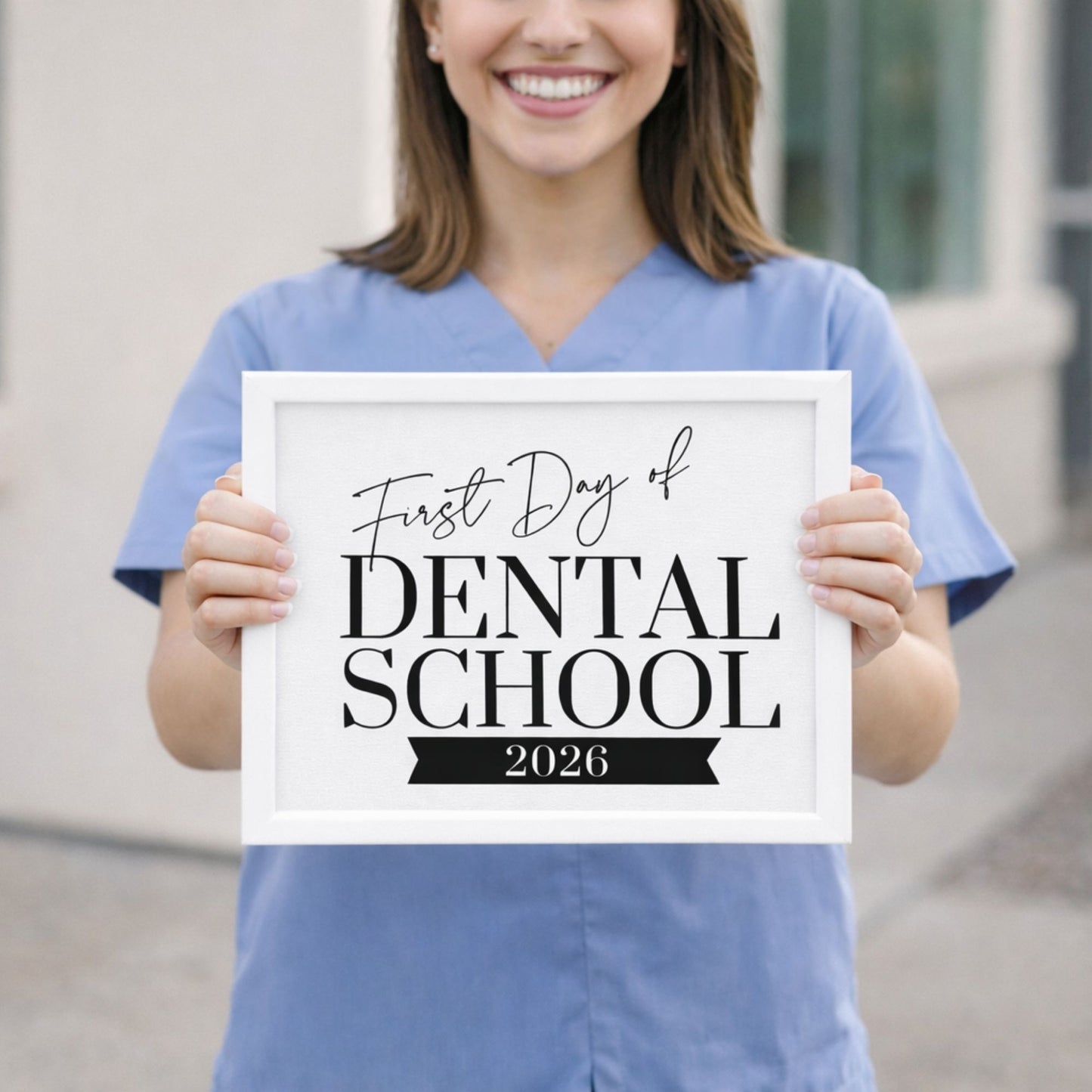 Person holding a sign for the 'First Day of Dental School 2026' in dental scrubs.