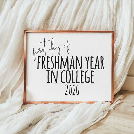 Framed sign with 'first day of Freshman Year in College 2026' text on a soft fabric background