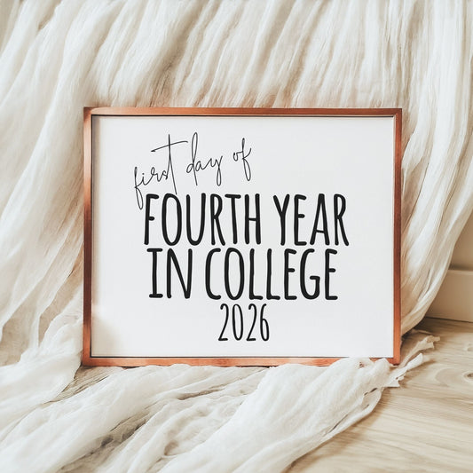 Framed sign with 'first day of fourth year in college 2026' text on a soft fabric background