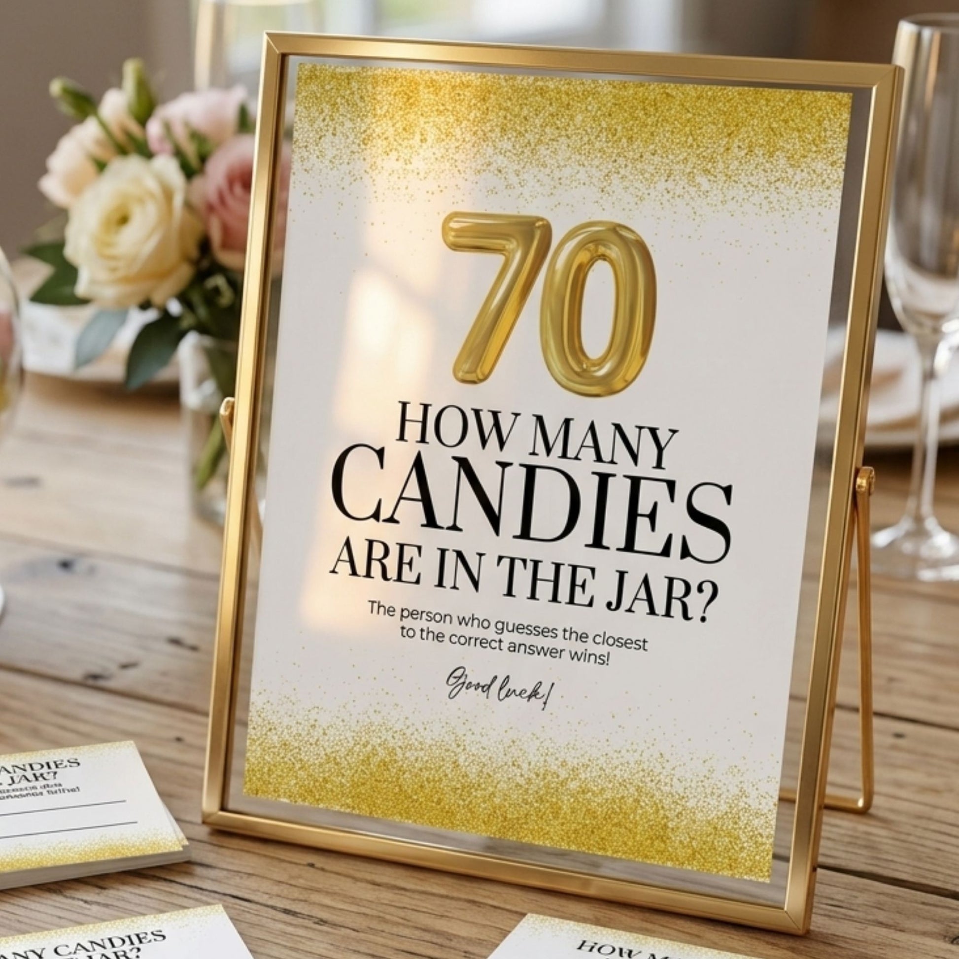 Framed 70th birthday game sign on a table with flowers and glasses in the background