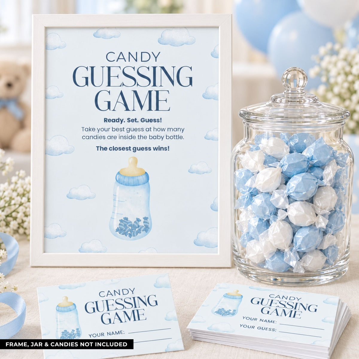 Baby shower candy guessing game set featuring a white-framed sign, a glass jar filled with blue and white wrapped candies, and matching printed ticket cards on a styled tabletop.