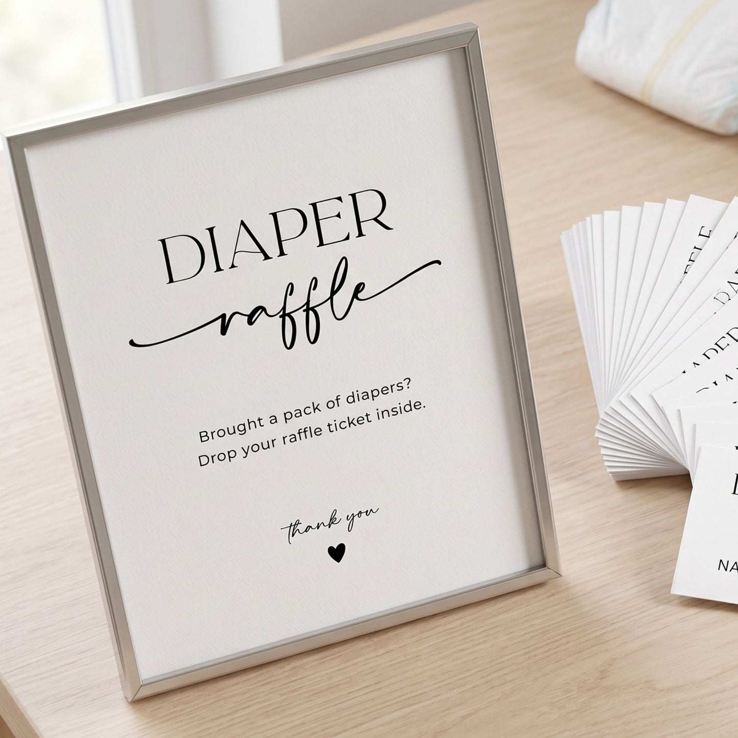 Framed sign for a diaper raffle with raffle tickets on a wooden surface
