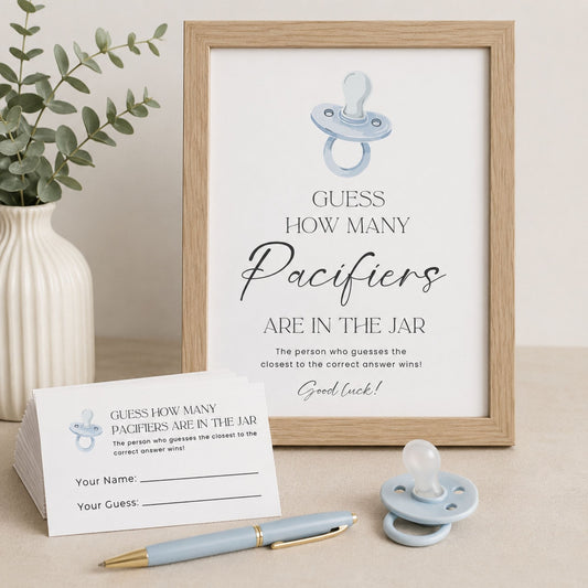 A framed baby shower game print reading 'Guess How Many Paciers Are in the Jar' with a pacifier illustration, shown on a tabletop with a small card, pen, and pacifier. No person or animal is present, and the scene is styled as a clean product display rather than a real lived-in environment, so Product/Packaging fits better than Lifestyle.