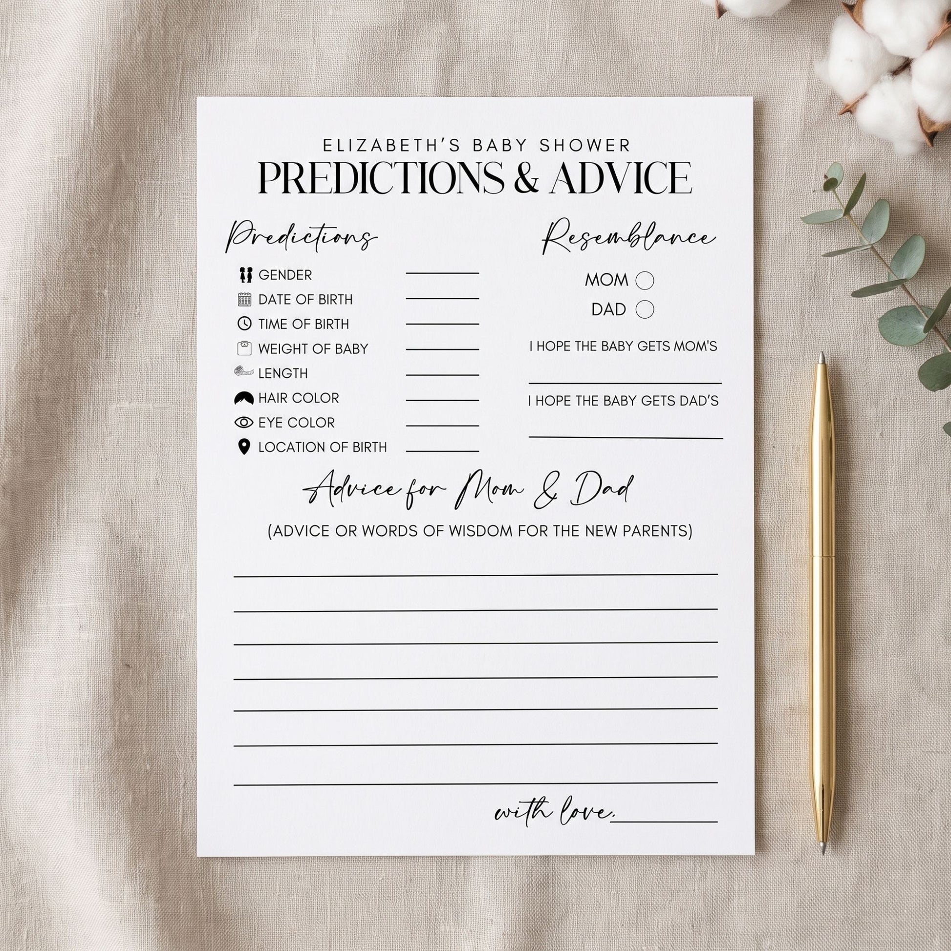A baby shower prediction and advice card laid flat on a light fabric surface, with a gold pen to the right and cotton stems and greenery at the top right. The card has printed fields for predictions, resemblance notes, and advice for mom and dad.