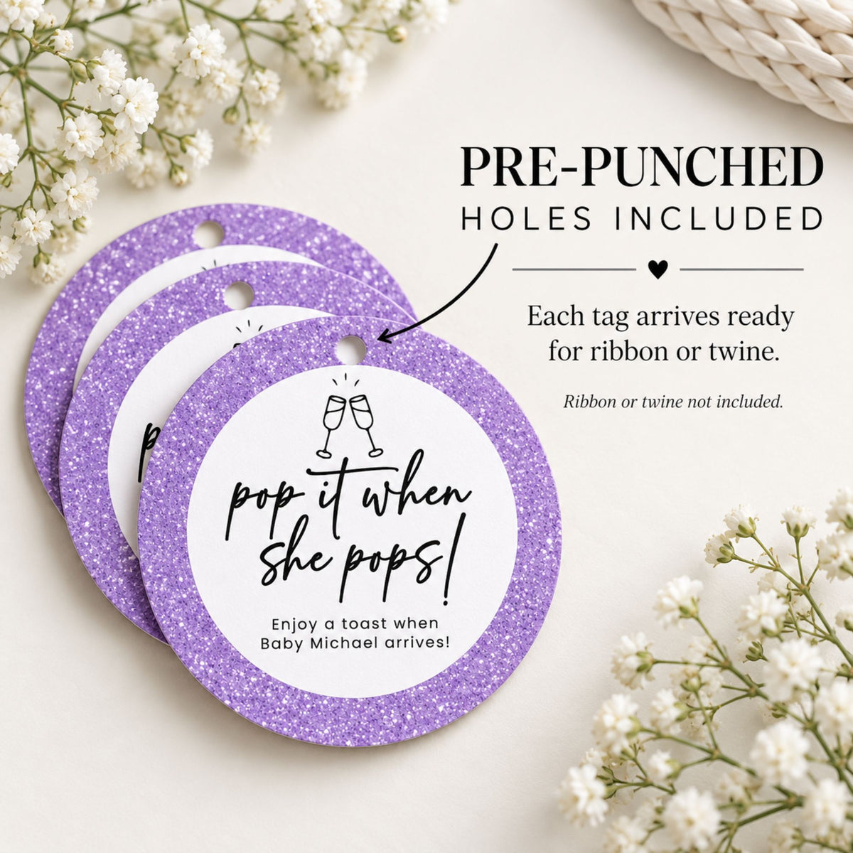 Three round purple glitter baby shower favor tags with white centers and pre-punched holes, arranged on a light cream background with white flowers and text explaining the product.