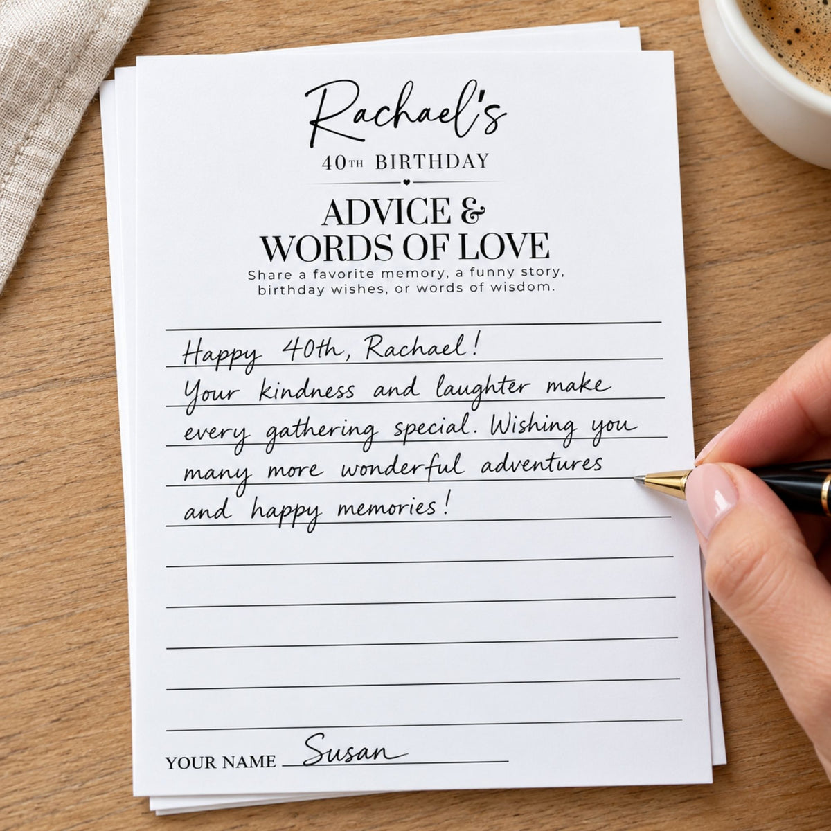 A stack of personalized birthday cards on a wooden table, with one card addressed to 'Rachael' for her 40th birthday. A hand holding a gold pen is writing on the card, with a coffee cup and fabric visible in the background.