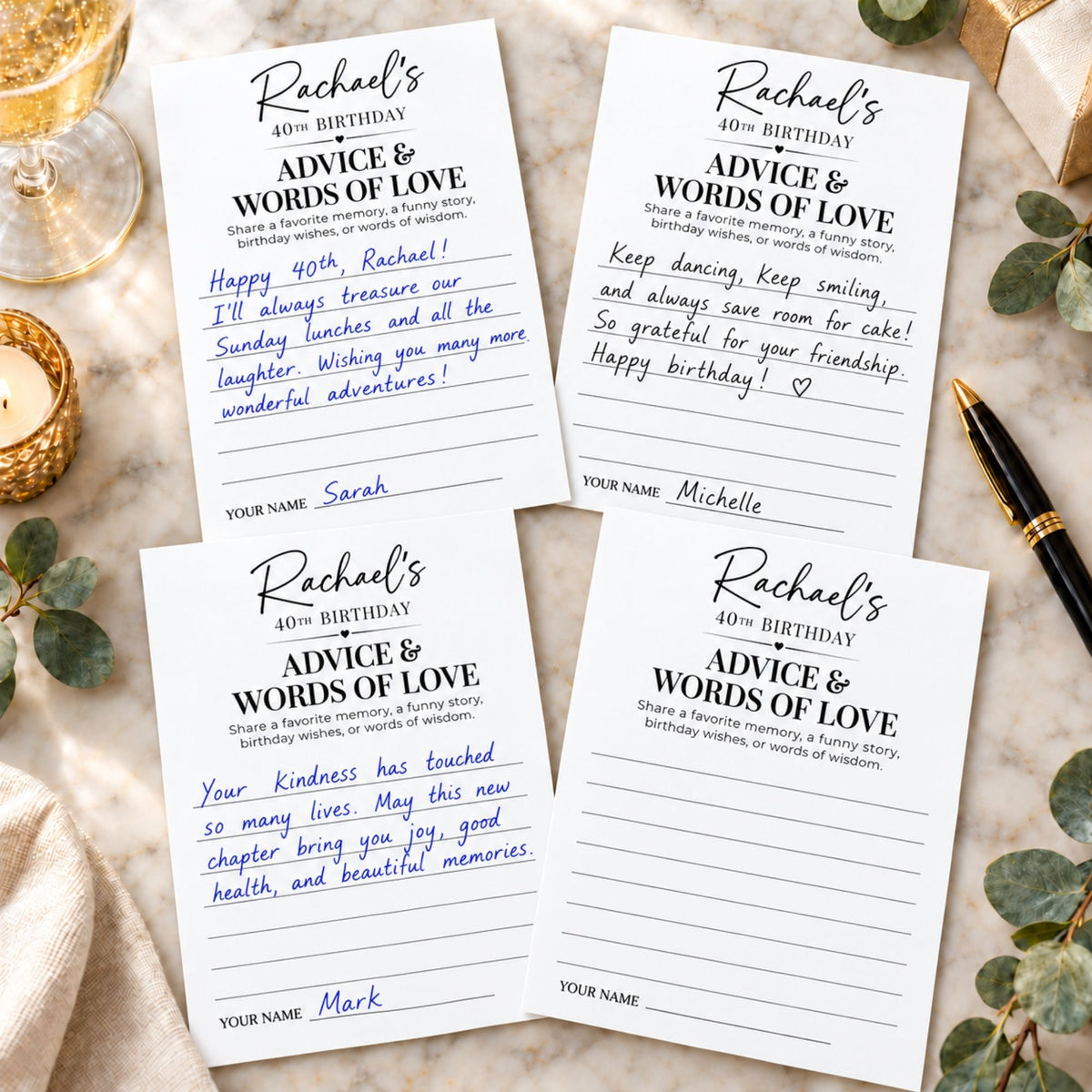 Four white birthday cards with printed black text reading 'Rachael's 40th Birthday' and 'Advice & Words of Love,' arranged on a light fabric surface with decorative props including a gold bowl, greenery, and a black pen.