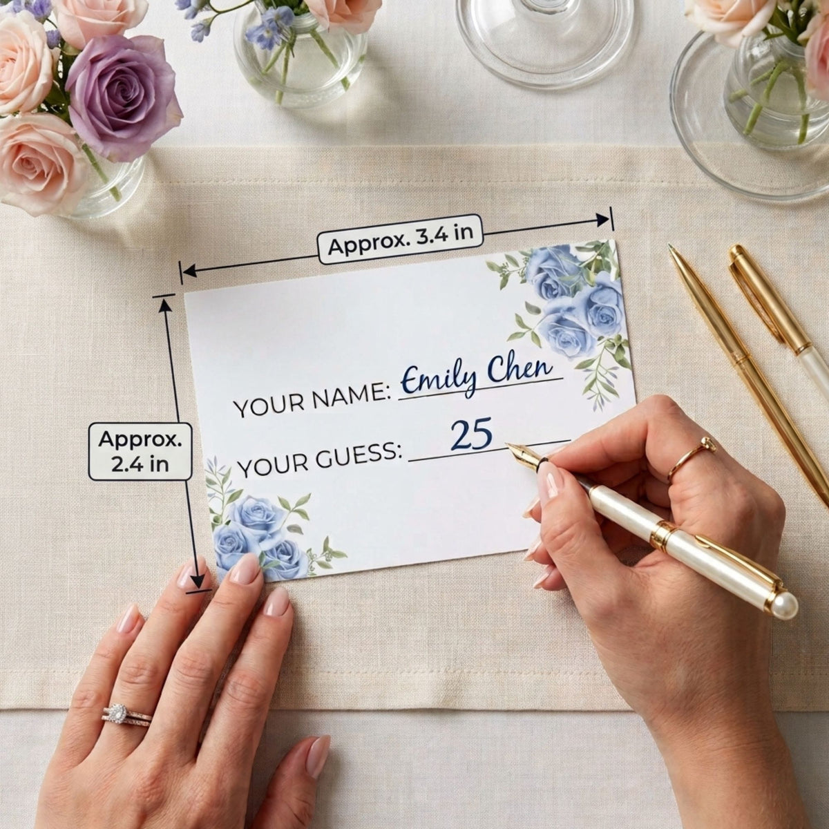 A personalized wedding guest list card with blue floral designs in the corners, held by two hands on a beige table runner. The card includes customizable text fields and dimension labels.