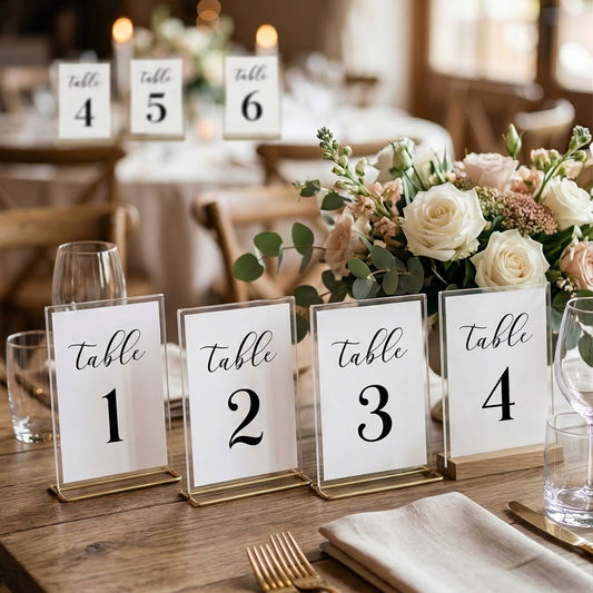 Table number signs on a set dining table with floral arrangement and glasses.