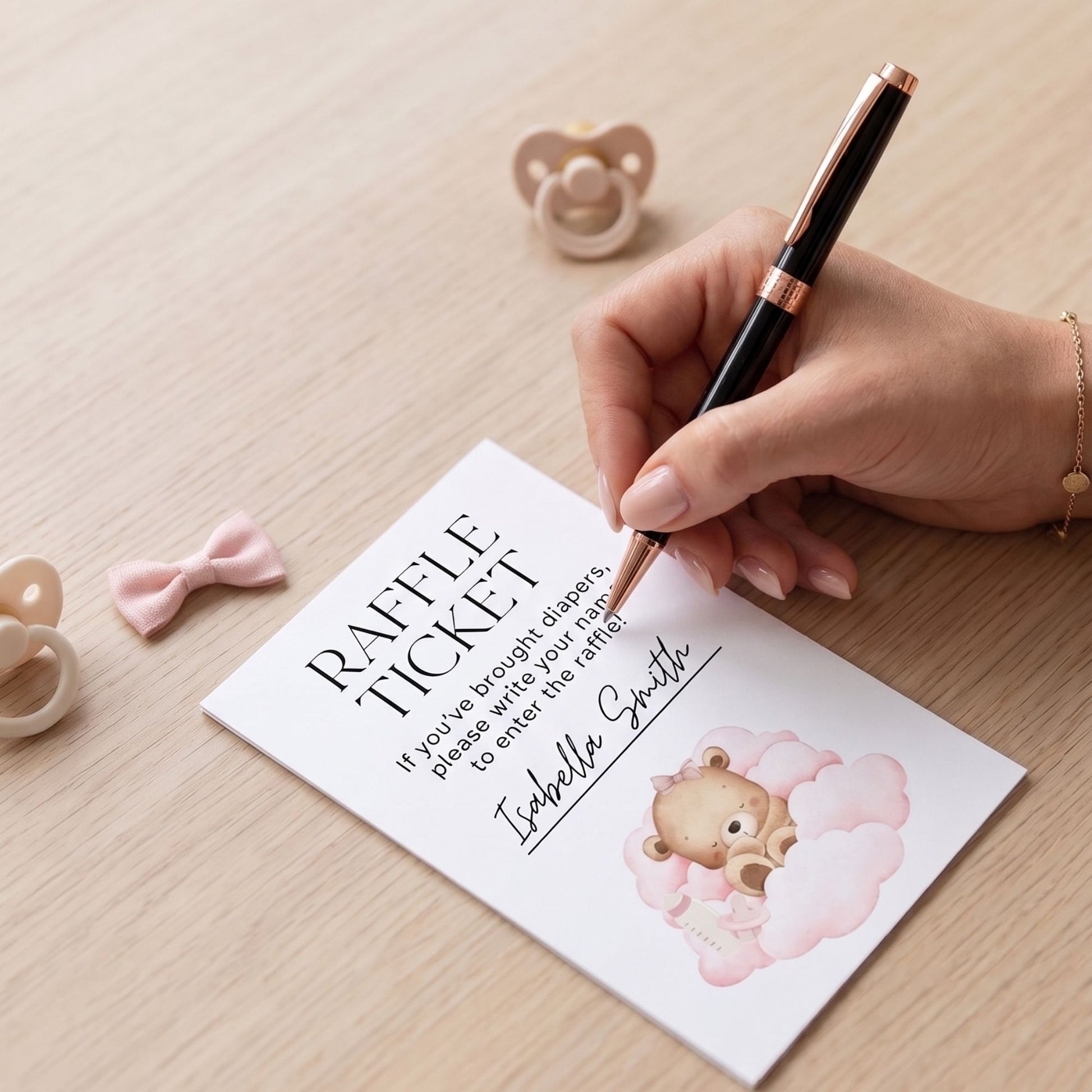 Hand writing on a raffle ticket with a teddy bear design, pacifiers in the background