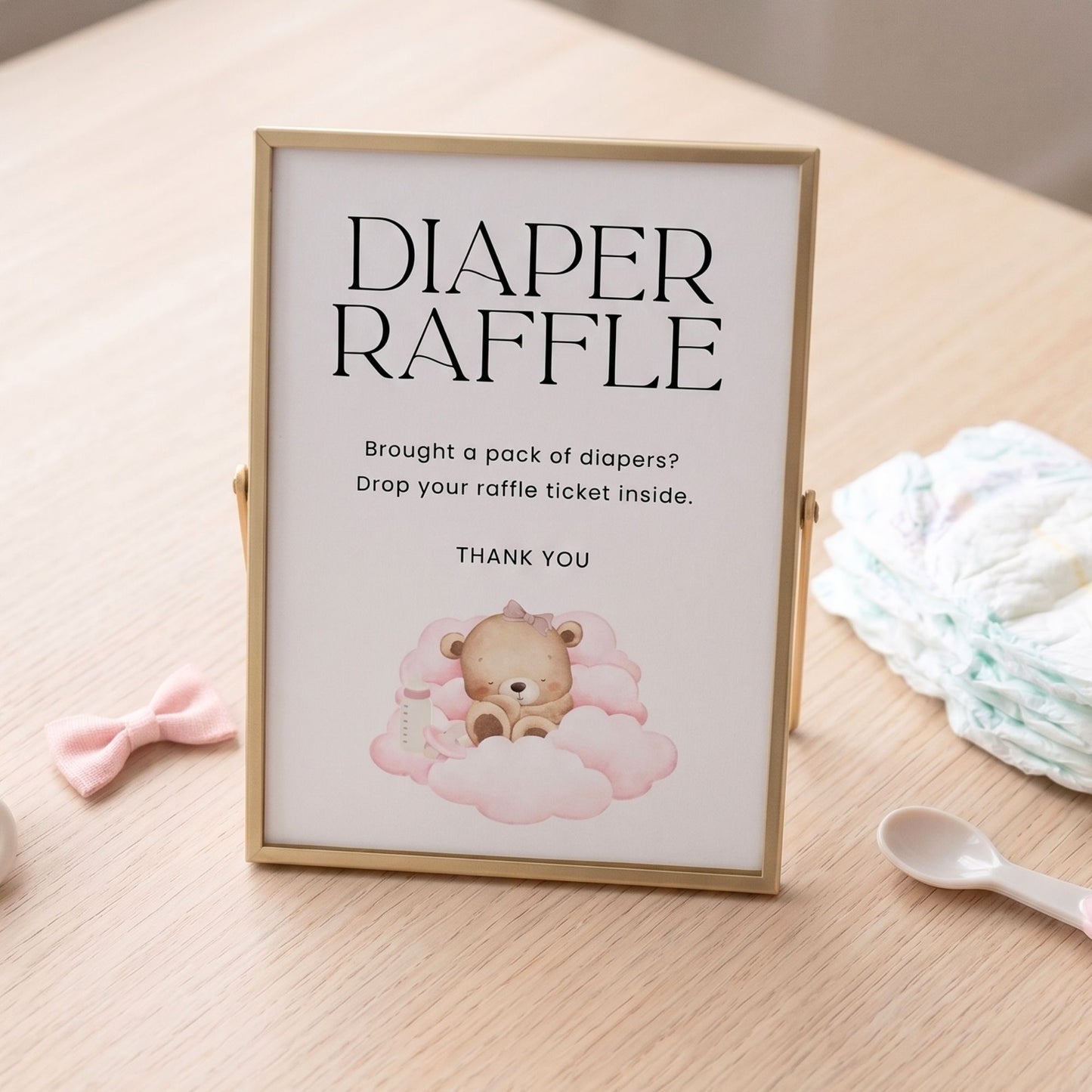Framed sign for a diaper raffle with a teddy bear illustration on a wooden surface.