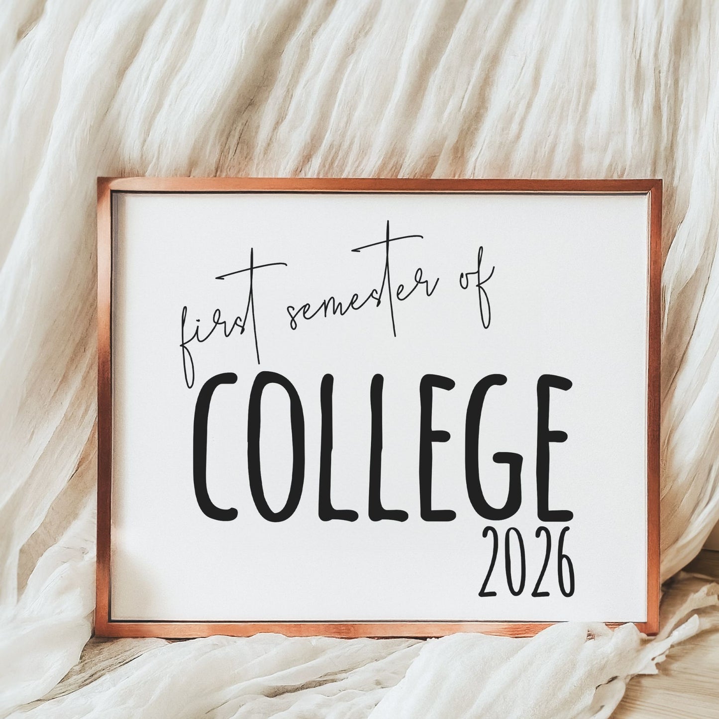 Framed sign with 'first semester of college 2026' text on a soft fabric background