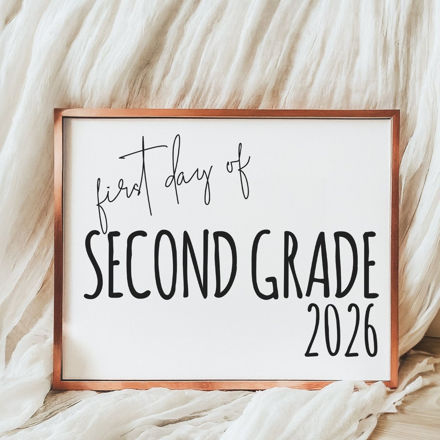 Sign with 'first day of second grade 2026' text on a soft fabric background