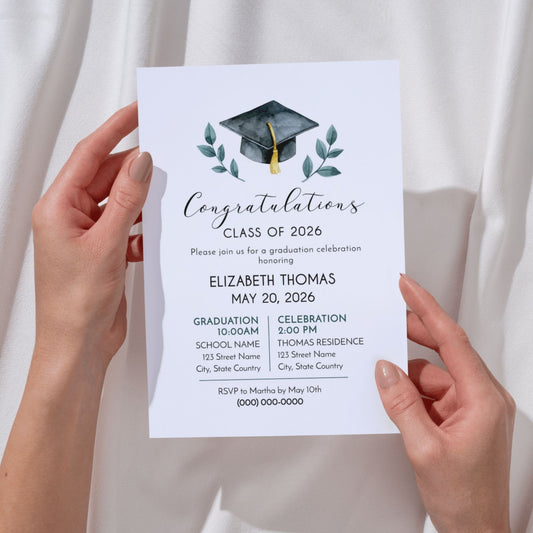 A pair of hands holds a vertical 5x7 graduation invitation. The design features a watercolor-style black graduation cap with a gold tassel, flanked by green leafy branches. The text reads "Congratulations Class of 2026" in a mix of script and serif fonts, honoring Elizabeth Thomas on May 20, 2026. Details for a 10:00 AM graduation and a 2:00 PM celebration at the Thomas Residence are included.