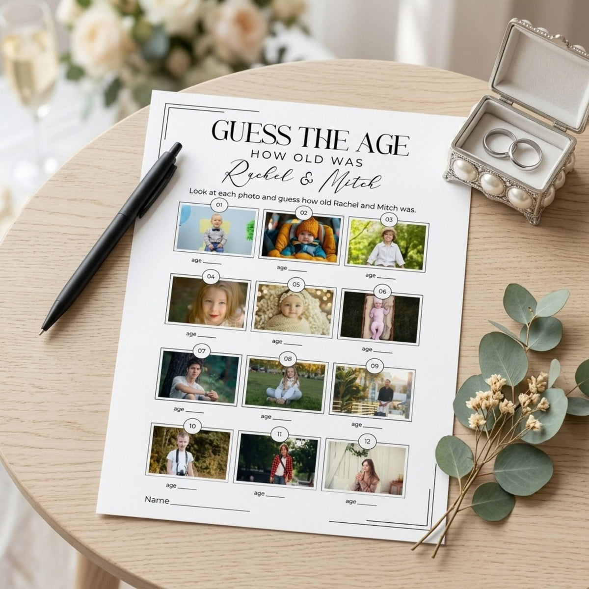 A personalized 'Guess the Age' photo puzzle sheet for Rachel & Mitch, styled on a light wood table next to a black pen, a small ring box, and eucalyptus leaves.