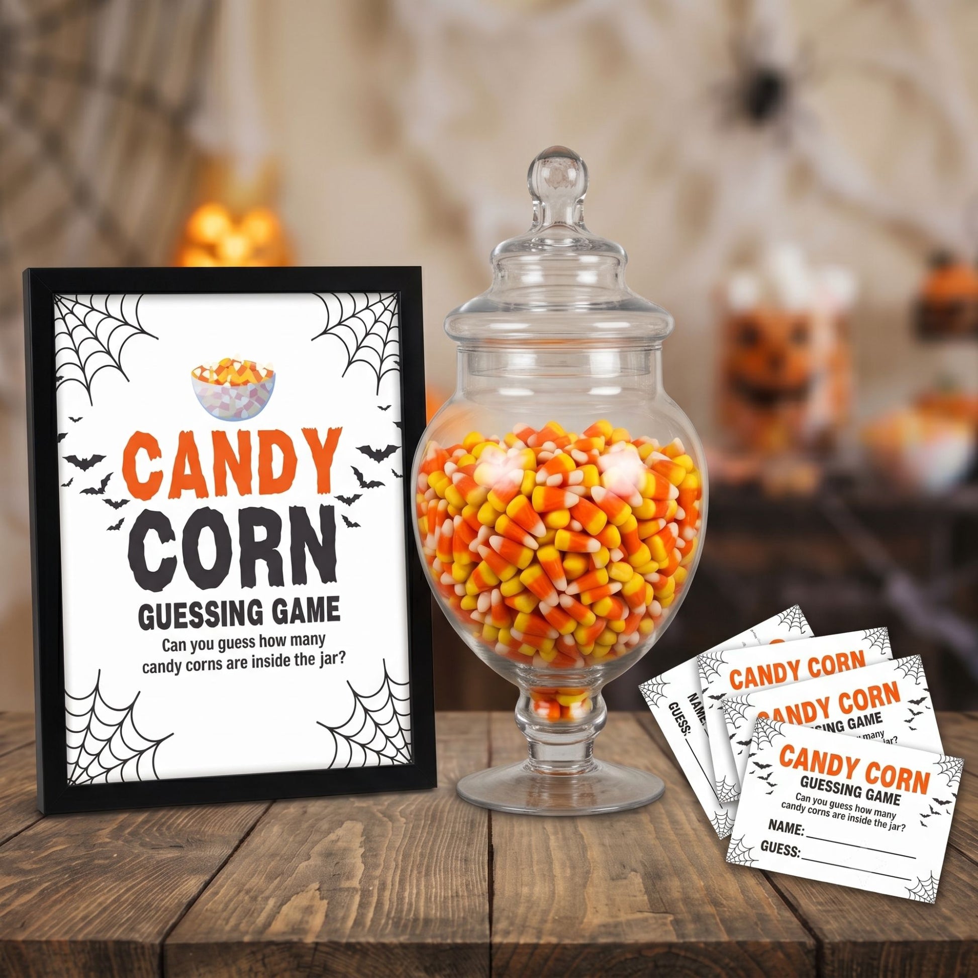 Halloween candy corn guessing game set featuring a black-framed sign, a large glass jar filled with candy corn, and several printed game tickets on a rustic wooden table.