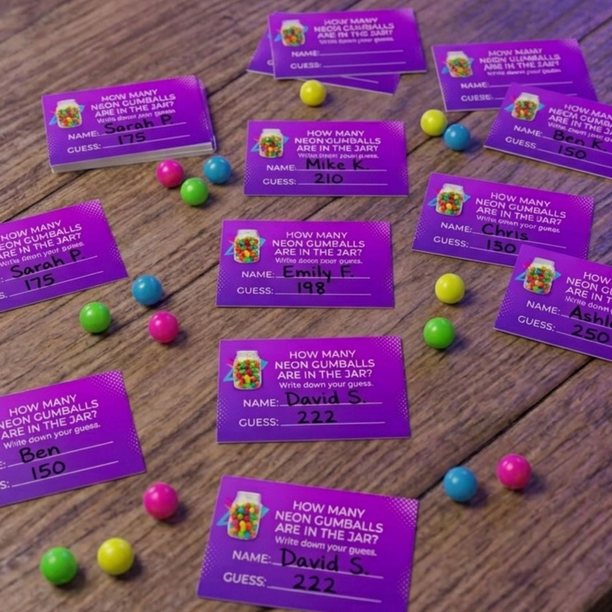 Purple trivia cards for 'Neon Cumbballs' and 'Neon Miceballs' scattered on a wooden table, surrounded by colorful round candy balls. The cards feature a colorful neon mouseball graphic and ask players to write down their guesses.