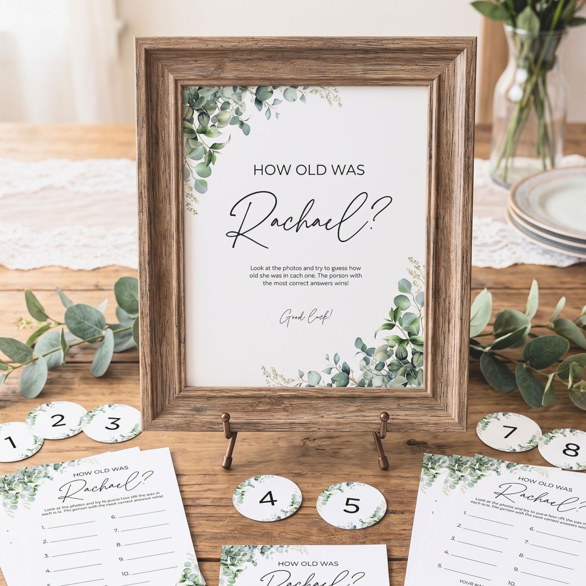 Decorative sign with 'How old was Rachel?' question on a wooden table with eucalyptus leaves.