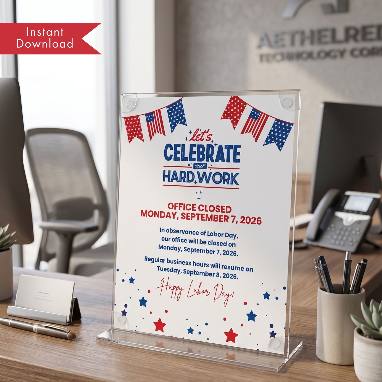 A clear acrylic desk sign displaying a Labor Day office closure notice with red, white, and blue text and American flag bunting, shown on a wooden desk in an office setting.