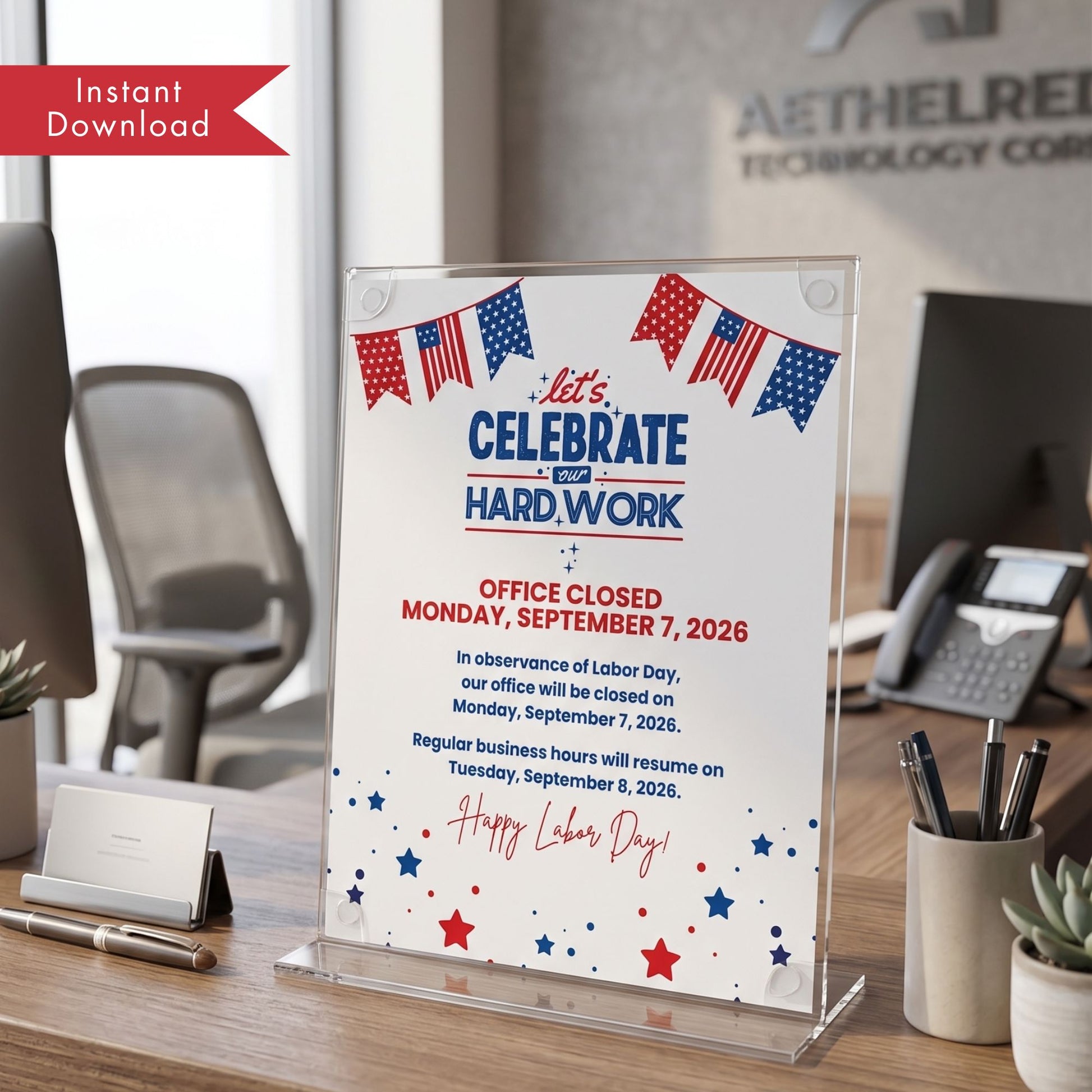 A clear acrylic desk sign displaying a Labor Day office closure notice with red, white, and blue text and American flag bunting, shown on a wooden desk in an office setting.