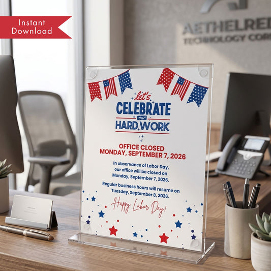A clear acrylic desk sign displaying a Labor Day office closure notice with red, white, and blue text and American flag bunting, shown on a wooden desk in an office setting.