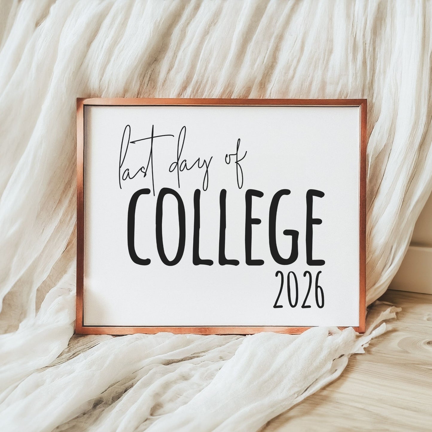 Framed sign with 'last day of college 2026' text on a soft fabric background