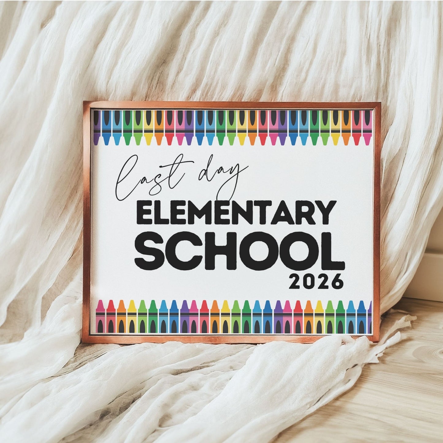 Framed sign with 'Last Day Elementary School 2026' text and colorful crayon illustrations on a textured fabric background.