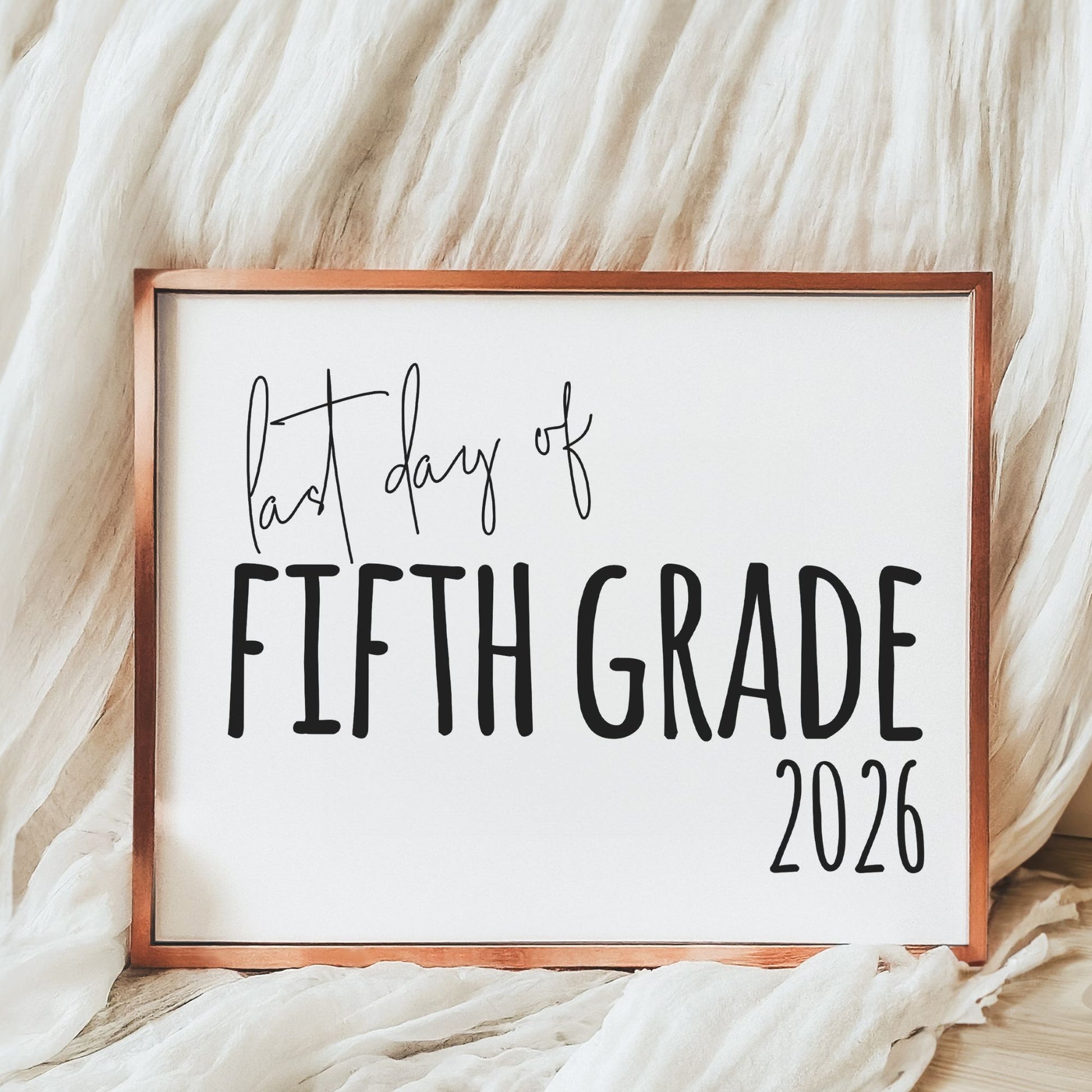 Decorative sign with 'Last day of Fifth Grade 2026' text on a soft fabric background