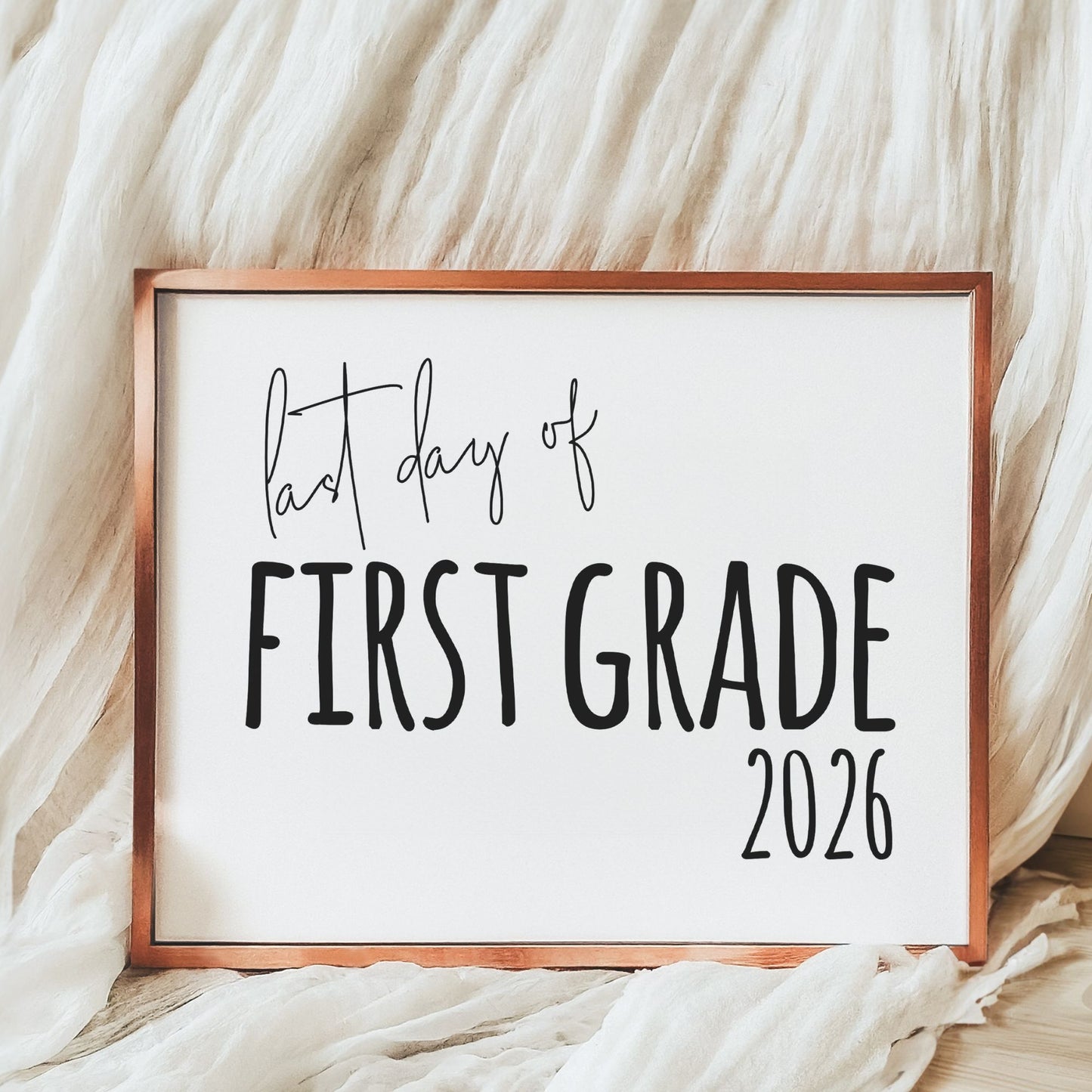 Decorative sign with 'last day of First Grade 2026' text on a soft fabric background