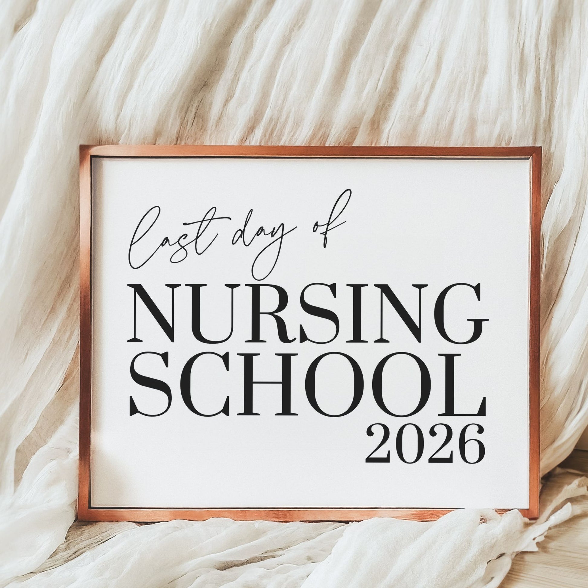 Framed sign with 'Last day of Nursing School 2026' text on a soft beige background