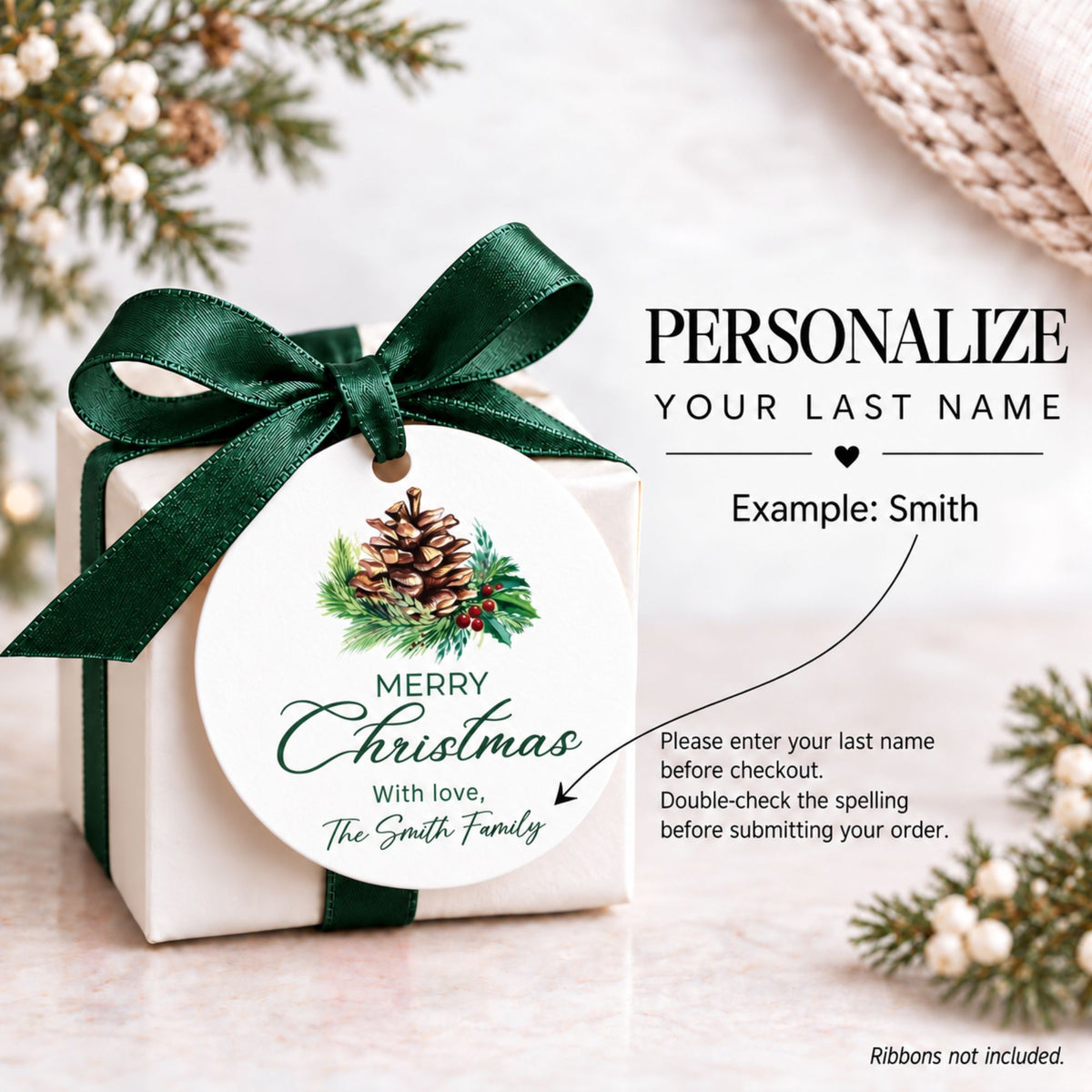 A small white gift box tied with a dark green satin ribbon and bow, featuring a round Christmas-themed tag that reads 'Merry Christmas With love, The Smith Family' with a pinecone illustration. The image includes overlaid text showing a customization example and instructions, on a softly styled holiday background with greenery and a knitted textile.