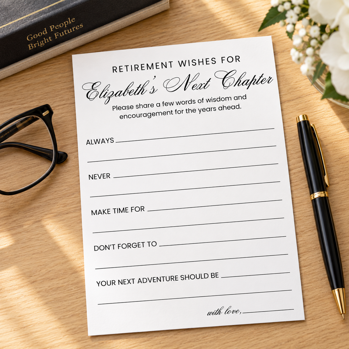 A retirement wishes card with elegant black script and printed lines, styled on a light wood tabletop with a black pen, eyeglasses, a book, and white flowers.