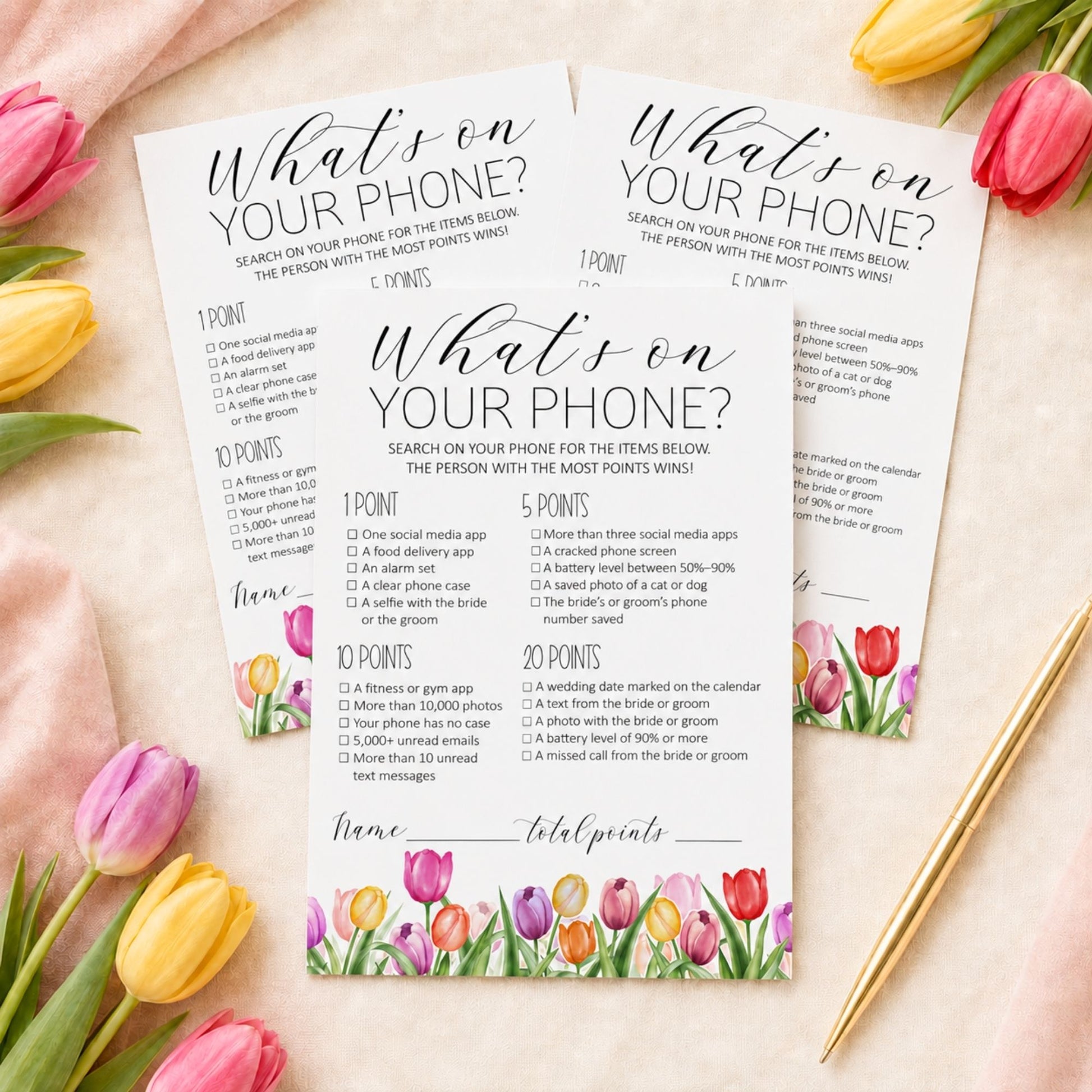 Two printed 'What's on YOUR PHONE?' game cards with watercolor tulip borders, styled in a flat lay with pink tulips and a gold spoon on a white background.
