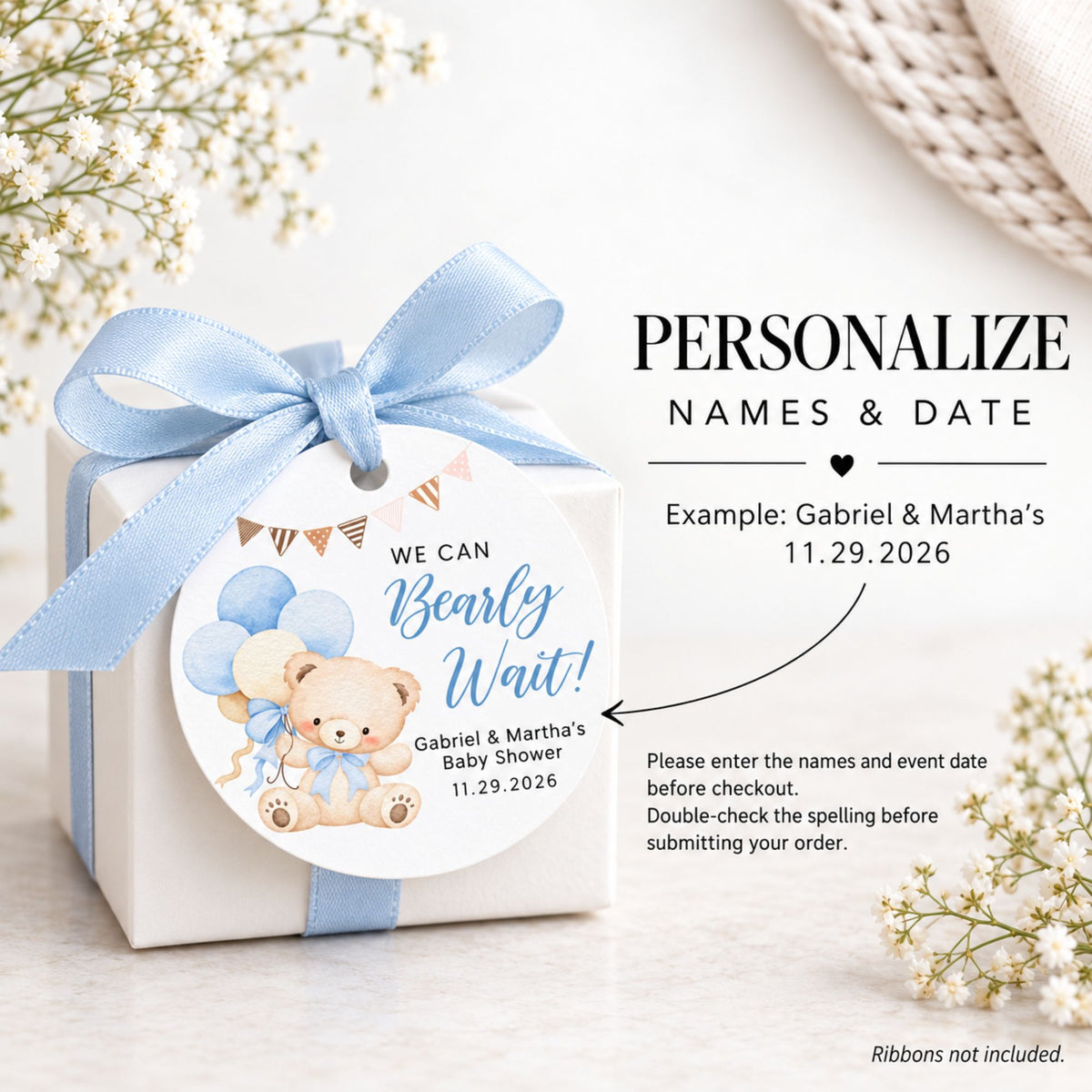 A white gift box tied with a light blue ribbon and a round custom tag reading 'WE CAN Bearly Wait!' for a baby shower, shown beside text that says 'PERSONALIZE NAMES & DATE' with example names and date. Decorative flowers and a woven textile appear around the scene.