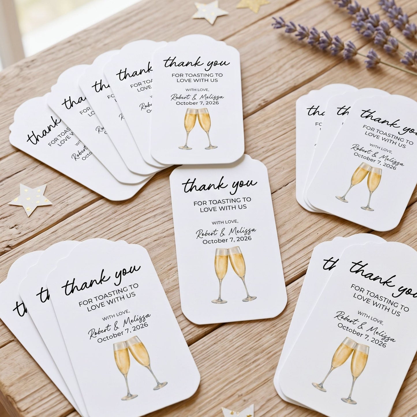 A set of white wedding toast cards with black script text and gold champagne glass illustrations, arranged on a wooden tabletop with decorative star and lavender props.