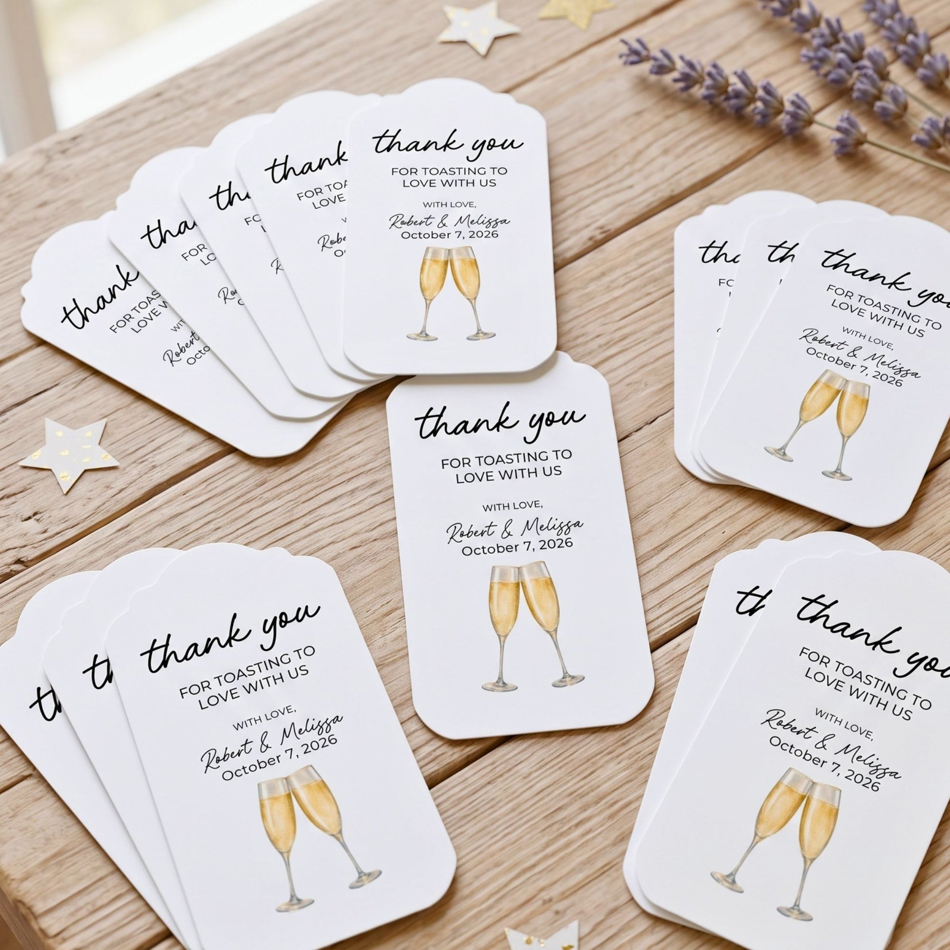 A set of white wedding toast cards with black script text and gold champagne glass illustrations, arranged on a wooden tabletop with decorative star and lavender props.