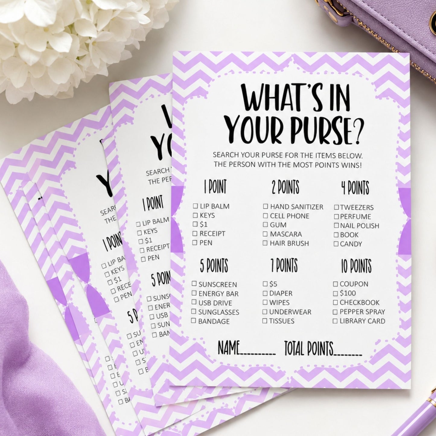 Three purple and white chevron checklist cards titled 'WHAT'S IN YOUR PURSE?' fanned out on a light surface, with white flowers and a lavender bag partially visible in the background.