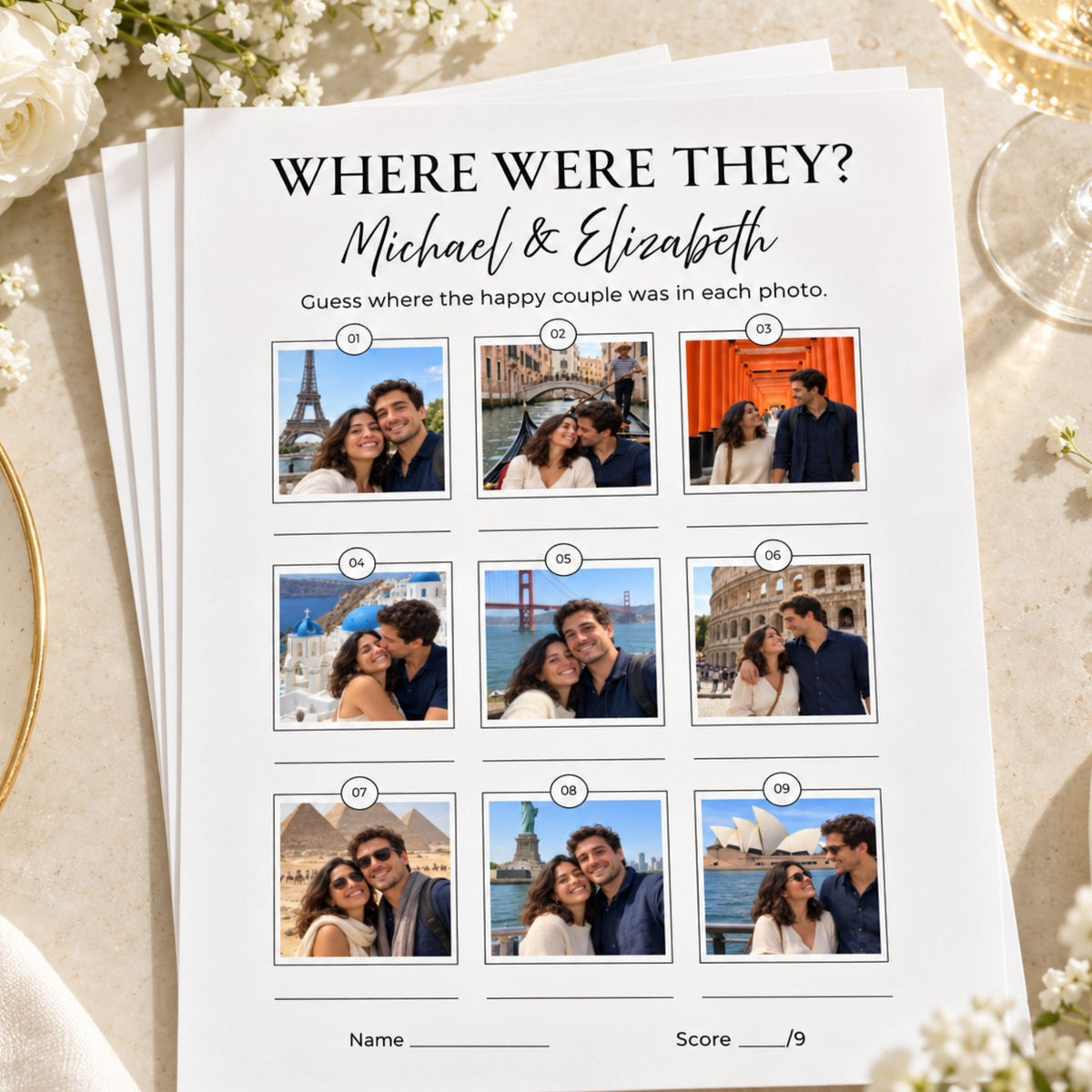 A printed wedding photo game sheet titled "WHERE WERE THEY? Michael & Elizabeth" lies on a light beige surface with decorative flowers and glassware around it. The sheet shows nine small couple photos with numbered labels and spaces for name and score at the bottom.