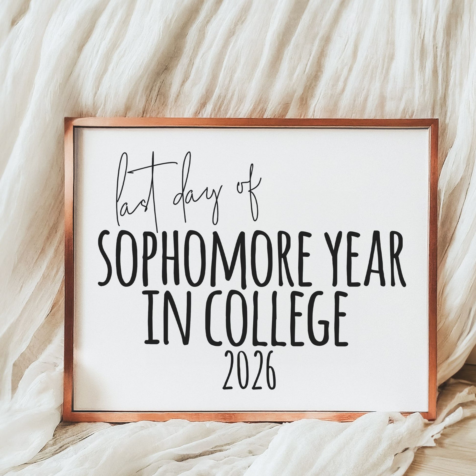 Framed sign with 'last day of sophomore year in college 2026' text on a textured fabric background