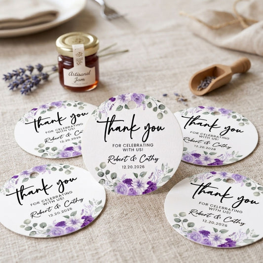 Five round white thank-you cards with purple floral watercolor designs and black script text, arranged on a beige fabric surface with a small jar of jam, lavender sprigs, and a wooden scoop in the background.